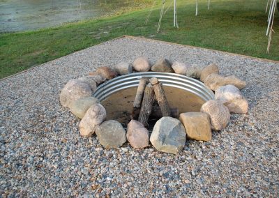 A fire pit with rocks around it and grass in the background.