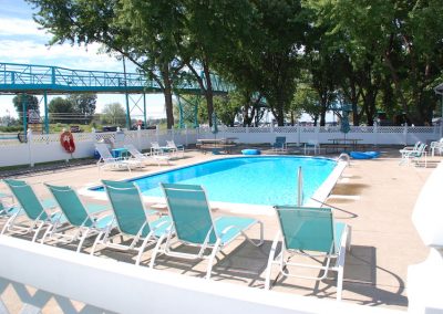 A pool with chairs and trees in the background