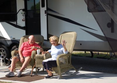 A man and woman sitting in lawn chairs outside of an rv.
