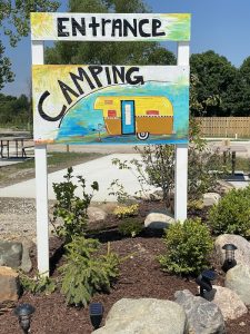 A sign that says camping with an rv camper on it.
