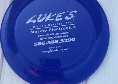 A blue frisbee with luke 's marine electronics written on it.
