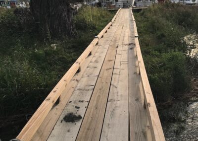 A wooden bridge that is in the middle of a field.